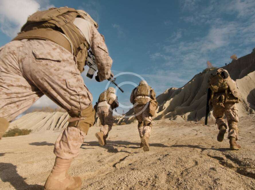 Soldiers running in a desert during a military exercise.