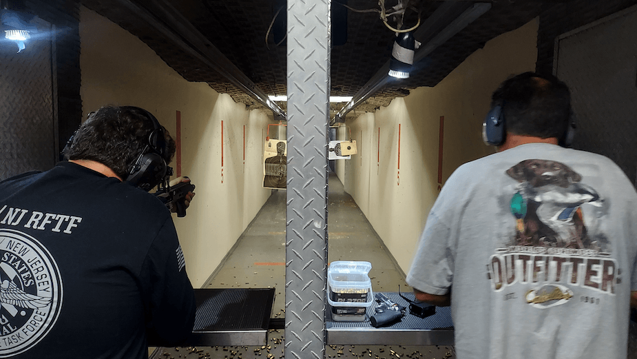 Two people shooting at an indoor gun range.